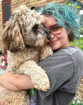 Lily, with dyed light blue hair, cuddling a dog