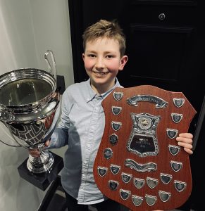 Henry holding his awards and trophies from his karting wins. 