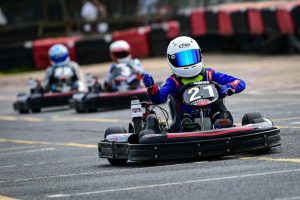 Henry competing in a go-kart numbered 21, with two karters racing to catch up with him. 