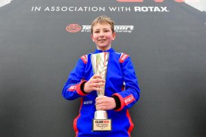 Henry holding his trophy in his racesuit, after winning the Club 100 race at Whilton Mill Racetrack. 